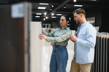 Bir hırdavatçıdaki seramik fayansları dikkatlice seçen çift, evlerini yenileme projesini planlıyorlar.