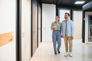 Hırdavatçıda el ele yürüyen genç bir çift yeni evleri için iç kapıları seçiyor.