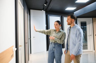 Nalbur dükkanındaki bir çifte farklı kapılar gösteren tezgahtar ev yenileme projeleri için doğru kapıyı seçmelerine yardım ediyor.