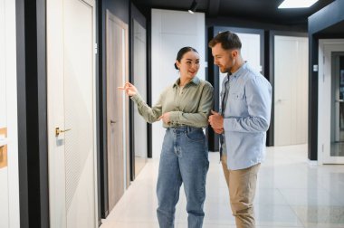 Mağazadaki bir çifte iç tasarım seçenekleri gösteren mağaza asistanı, doğru kapıyı seçmelerine yardımcı oluyor.