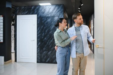 Bir nalbur dükkanında yeni iç kapılar seçen çift, ev yenilemesi hakkında tartışıyor ve karar veriyor