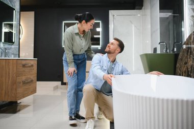 Genç bir çift, banyo mobilyası mağazasında yeni bir küvet seçiyor. Ev yenileme projeleri hakkında tartışıyor ve kararlar alıyorlar.