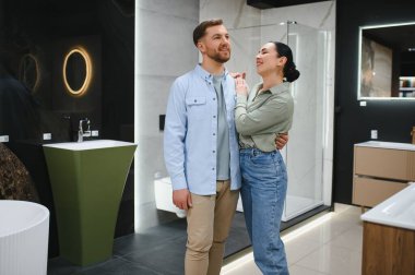 Tesisatçı dükkanındaki banyo demirbaşlarını seçerken kucaklaşan çift evlerini yenilemeyi planlıyor.