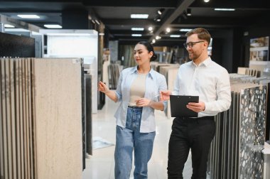 Seramik fayans ve tesisat mağazasında müşterilere danışmanlık yapan bir tezgahtar. Farklı seçenekleri seçip göstermesine yardımcı oluyor.