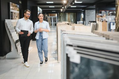 Satıcı elinde seramik seramik seramik koleksiyonu hırdavatçıda yürüyen kadın müşteriye gösteriyor.