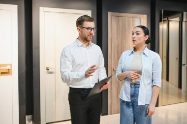 Kapılar ve pencereler mağazasındaki müşterilere iç tasarım çözümleri gösteren panolu bir mağaza asistanı