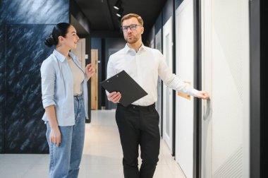 Kadın müşterilere modern iç kapılar gösteren profesyonel bir satıcı elinde bir pano, mobilya mağazasında danışmanlık yapıyor.