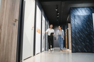 Hırdavatçıda çalışan bir kadına farklı kapılar gösteren tezgahtar dairesine yeni bir kapı seçiyor.