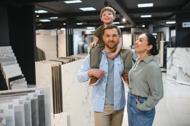 Modern bir hırdavatçıda seramik seramik seramik döşeme seçerek alışveriş yaparken kaliteli vakit geçirmeyi seven mutlu bir aile.