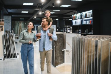 Mutlu aile, canlı bir yapı malzemesi mağazasında kaliteli zaman geçirirken ev yenileme için seramik fayanslar seçiyor.