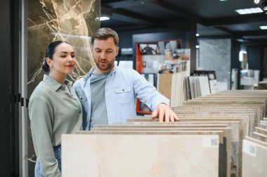 Bir hırdavatçıda seramik fayanslar seçen çift, ev yenileme projeleri için çeşitli seçenekleri araştırıyor