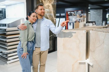 Mutlu çift bir hırdavatçıda seramik fayanslara sarılıp onları işaret ediyor ve evlerini yenilemek için plan yapıyorlar.