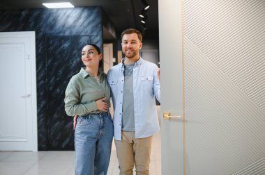 Gülümseyen bir çift modern bir mağazada seramik fayans ve tesisat seçeneklerini inceliyor, ev yenileme ve iç tasarıma ilgi gösteriyor