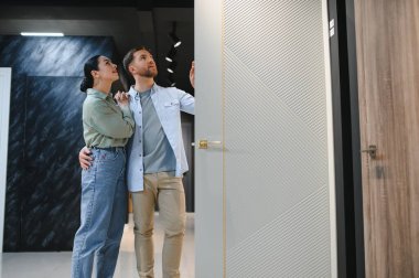 Mobilya mağazasında modern iç kapıları seçen genç çift, farklı seçeneklere ve tasarımlara bakıyor.
