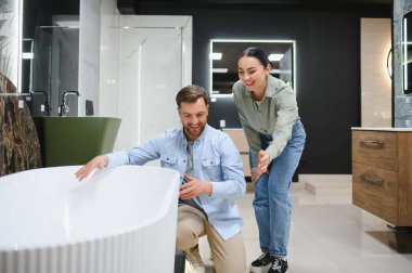 Tesisat ve banyo mobilyası mağazasında seramik küveti seçen mutlu çift, yeni ev dekorasyonunun keyfini çıkarıyor.