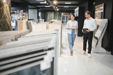 Mağazadaki seramik fayansları seçen bir müşteriye satış sırasında danışmanlık yapan bir tezgahtar.