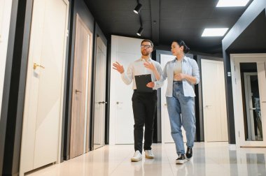 Kapılar ve fayanslar konusunda uzmanlaşmış bir mağazada yürüyen kadın müşterilere iç tasarım seçenekleri sunan satıcı.