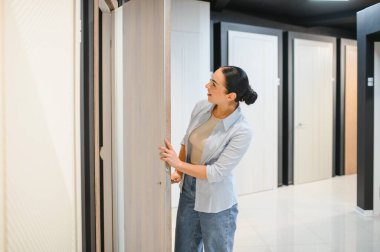 Müşteri, ev geliştirme seçeneklerini göz önünde bulundurarak, kapı ve pencerelerdeki çeşitli numuneleri incelerken bir iç kapı açıyor