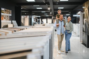 Mutlu aile, çeşitli seçeneklerle dolu modern bir nalbur dükkanının keyfini sürerken, ev yenilemeleri için seramik fayanslar seçiyor.