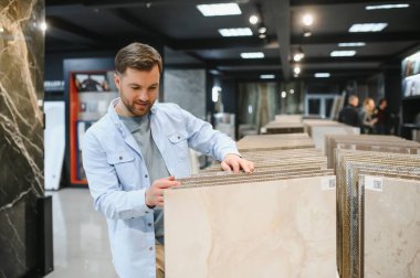 Bir perakende mağazasından seramik fayanslar seçen müşteri, bir ev geliştirme projesi için örnekler inceliyor