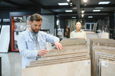 Seramik fayanslar seçen çiftler, özel bir mağazadaki banyo yenileme projeleri için çeşitli seçenekleri araştırıyorlar.