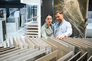 Bir hırdavatçıda seramik fayanslar seçen çiftler, ev yenileme projeleri hakkında tartışıyor ve kararlar alıyorlar.