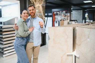 Ev dekorasyonu mağazasında seramik fayanslara sarılıp onları işaret eden mutlu çift evlerini yenilemek için planlar yapıyor.