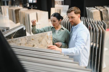 Modern bir hırdavatçıda seramik seramik seramik seramik seramik döşemeleri gözden geçiriyorlar, stil ve kaliteyi göz önünde bulundurarak.