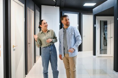 Mobilya mağazasının iç kapılarını seçen genç çift, stil ve malzemeler konusunda satış asistanından tavsiye alıyor.