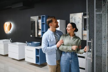Mutlu çift yeni bir banyo kaplaması seçiyor, sarılma ve gülümseme, bir banyo mobilya mağazasında, bir ev yenileme sırasında