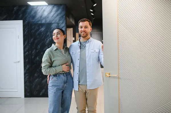 Gülümseyen bir çift modern bir mağazada seramik fayans ve tesisat seçeneklerini inceliyor, ev yenileme ve iç tasarıma ilgi gösteriyor