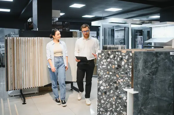 Satıcının elinde modern seramik ve tesisat dükkanlarındaki müşterilere farklı seramik fayanslar gösteren bir pano var.