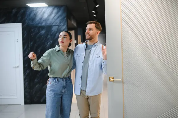 Birkaç kişi seramik fayansları ve tesisat tesisatlarını inceliyor. Ev yenileme projesi seçeneklerini tartışıyorlar. Meşgul ve düşünceli görünüyorlar.