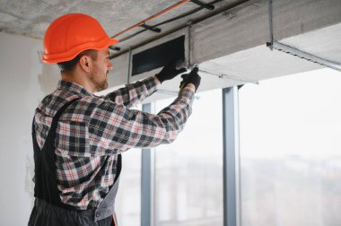 Hvac teknisyenleri inşaat halindeki bir binaya havalandırma kanalı döşüyorlar, modern bir çalışma alanında beceri ve hassasiyet gösteriyorlar.