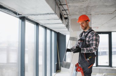 İnşaat alanına havalandırma boruları döşeyen bir miğfer takan inşaatçı, HVC sistemlerindeki hassasiyet ve uzmanlığa odaklanıyor.