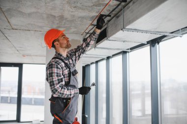 Hvac teknisyeni inşaat halindeki bir binaya havalandırma ve havalandırma boruları kuruyor.