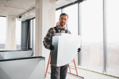 Hvac teknisyeni inşaat halindeki bir binada havalandırma sistemi kurulumu için metal havalandırma kanalı taşıyor.