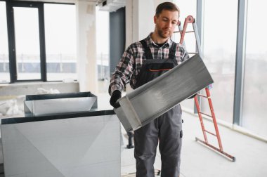 Hvac teknisyenleri inşaat halindeki bir binada dikdörtgen havalandırma kanalları kurarak uygun hava akışını ve iklim kontrolünü sağlıyorlar.