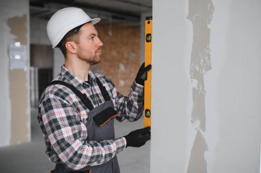 İnşaat veya ev tadilatı sırasında ruh seviyesini kullanarak duvarın dikeyliğini kontrol eden yapıcı