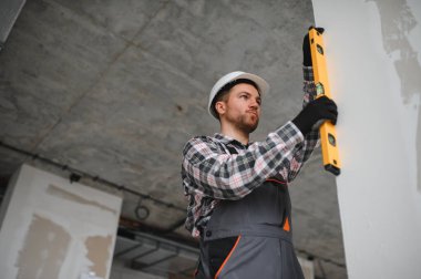 İnşaat sırasında ruh seviyesini kullanarak alçıpan panelinin dikey hizalanmasını denetleyen yapıcı