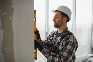 İnşaat veya ev yenilenmesi sırasında seviye aracını kullanarak duvarın dikeyliğini denetleyen yapıcı