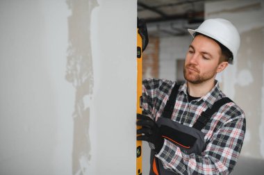 İnşaatçı bina veya ev yenileme sırasında ruh seviyesini kullanarak duvarın dikeyliğini kontrol eder