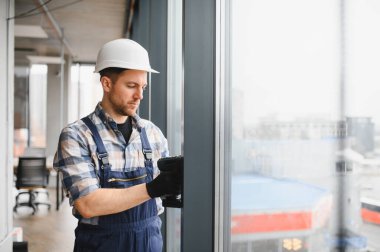 Profesyonel müteahhit kablosuz tornavida kullanır, yeni bir ofis binasına pencere çerçeveleri yerleştirir, hassas ve güvenli yerleştirme sağlar