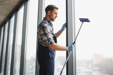 Modern bir ofis binasının camlarını silmek için cam temizleyicisi kullanıyor. Pırıl pırıl parlıyor.