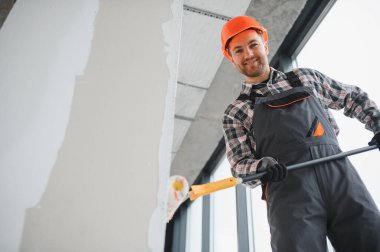 Modern bir binanın duvarını boyamak için patenci kullanarak inşaat ve onarım işlerinde usta bir müteahhit.