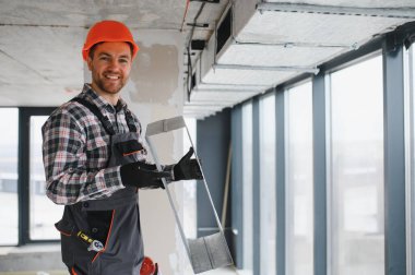 Hvac teknisyeninin elinde havalandırma kanalı var. Modern bir binaya havalandırma sistemi kuruyor.