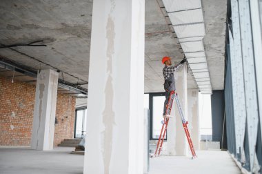 İnşaat halindeki bir binada havalandırma sistemi kurulumu üzerinde çalışan elektrikçi, uygun hava akımını ve konforu sağlıyor.