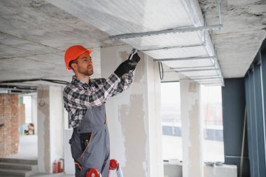 İnşaat işçisi inşaat halindeki bir binaya havalandırma sistemi kuruyor, düzgün bir hava akışı ve rahat bir ortam sağlıyor.