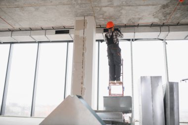 İnşaat işçisi inşaat halindeki bir binaya havalandırma ve havalandırma sistemi kuruyor.