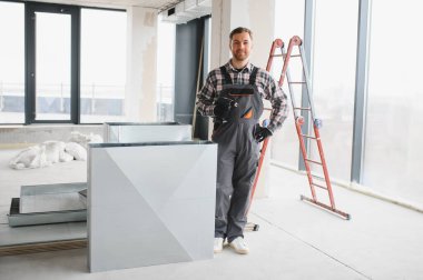 Hvac teknisyeni elinde kablosuz bir tornavida tutuyor ve yenileme veya inşaat sırasında modern bir ofis binasına havalandırma sistemi kuruyor.